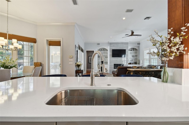 kitchen with pendant lighting, a large fireplace, ornamental molding, and sink