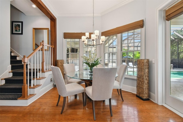 dining area featuring hardwood / wood-style flooring, crown molding, an inviting chandelier, and a wealth of natural light