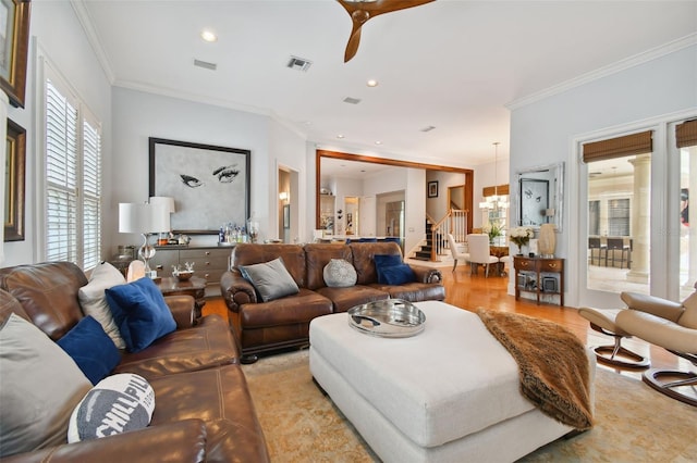 living room featuring crown molding, ceiling fan with notable chandelier, and light wood-type flooring