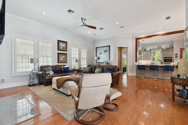 living room with crown molding, a healthy amount of sunlight, and light wood-type flooring