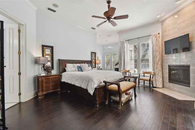 bedroom with crown molding, a fireplace, dark hardwood / wood-style floors, and ceiling fan