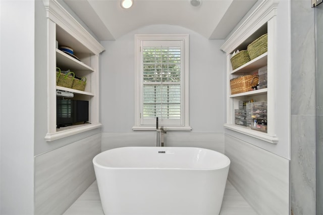 bathroom with a washtub, built in features, and lofted ceiling