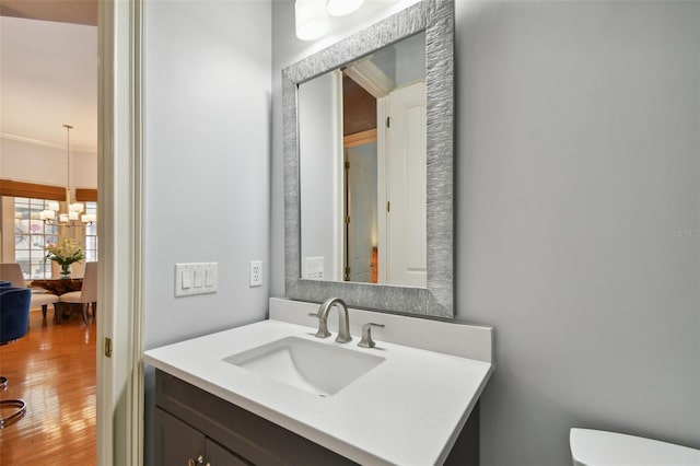 bathroom with vanity, hardwood / wood-style floors, a notable chandelier, and toilet