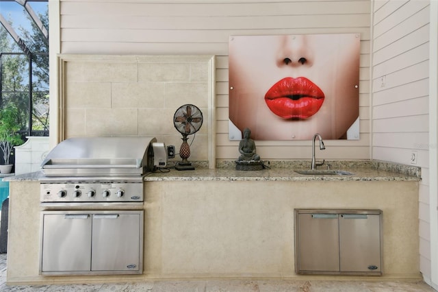 kitchen featuring sink, wooden walls, light stone counters, and decorative backsplash