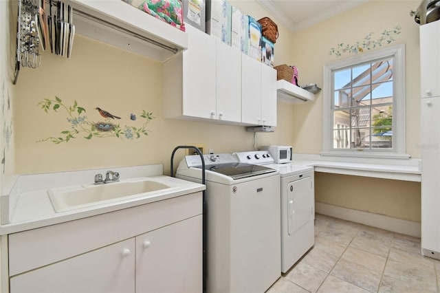 laundry area with washing machine and clothes dryer, sink, crown molding, cabinets, and light tile patterned floors