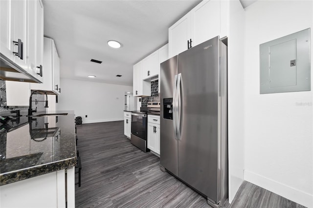 kitchen featuring white cabinets, backsplash, dark stone counters, electric panel, and stainless steel appliances