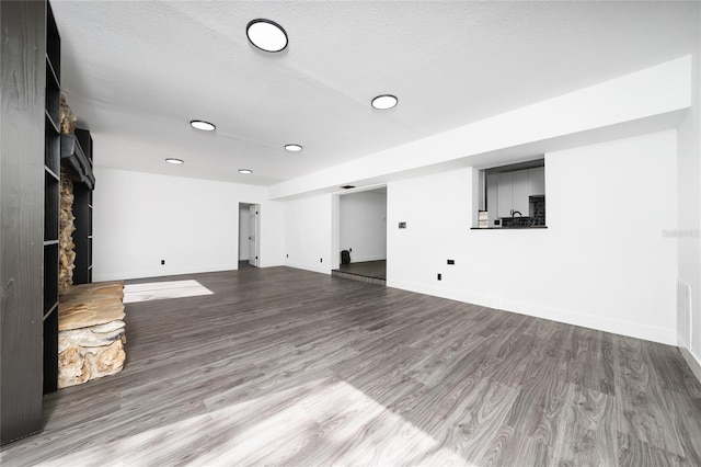 unfurnished living room with a stone fireplace, a textured ceiling, and light wood-type flooring