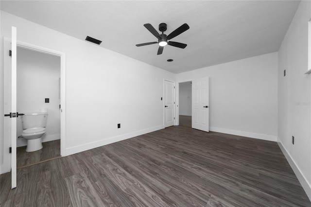 unfurnished bedroom featuring ensuite bathroom, dark wood-type flooring, and ceiling fan