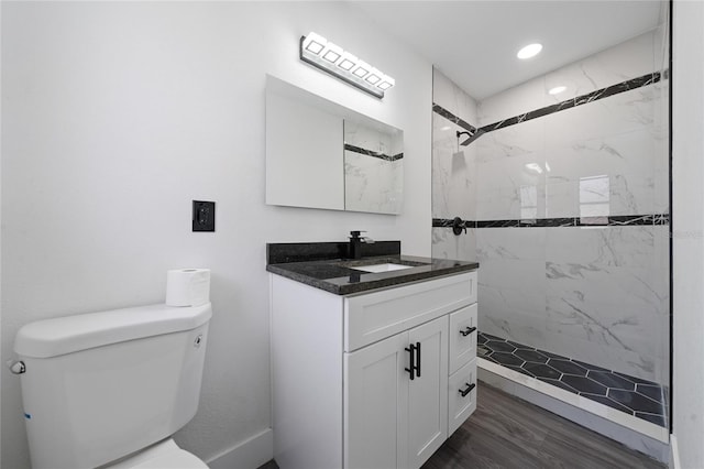 bathroom with vanity, hardwood / wood-style flooring, toilet, and tiled shower