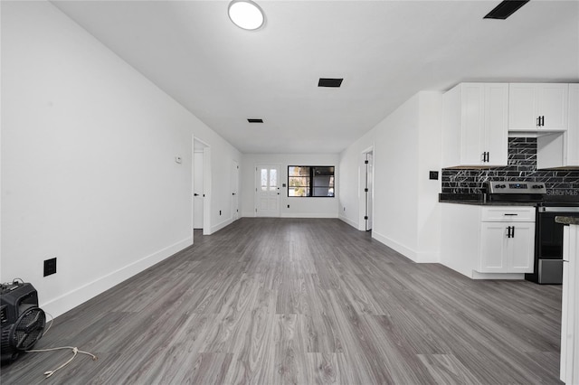 unfurnished living room with light wood finished floors, visible vents, and baseboards