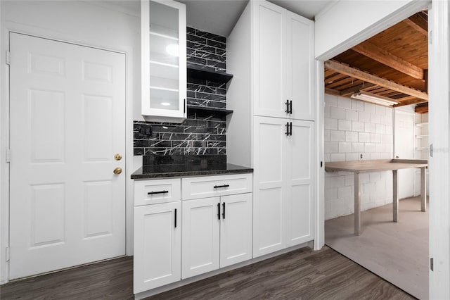 kitchen with dark stone counters, dark wood-type flooring, glass insert cabinets, and white cabinetry