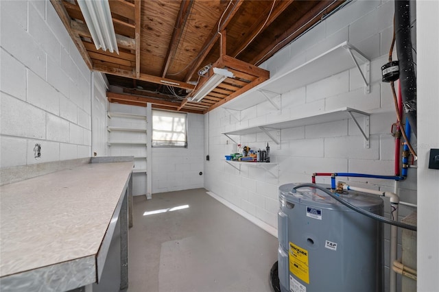 below grade area featuring water heater and concrete block wall