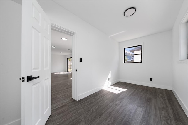 unfurnished room with plenty of natural light, baseboards, and dark wood-type flooring