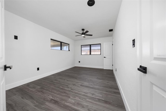 spare room with dark wood-style floors, visible vents, a ceiling fan, and baseboards