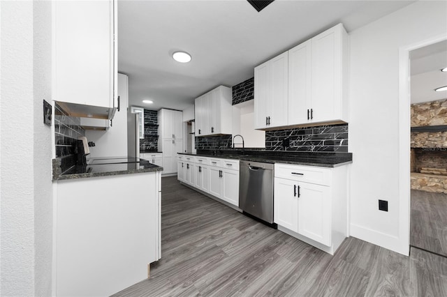 kitchen featuring tasteful backsplash, white cabinets, stainless steel dishwasher, and wood finished floors