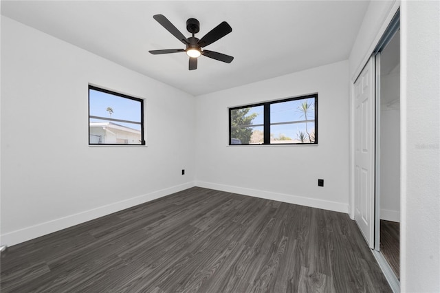 unfurnished bedroom with ceiling fan, dark wood-type flooring, a closet, and baseboards