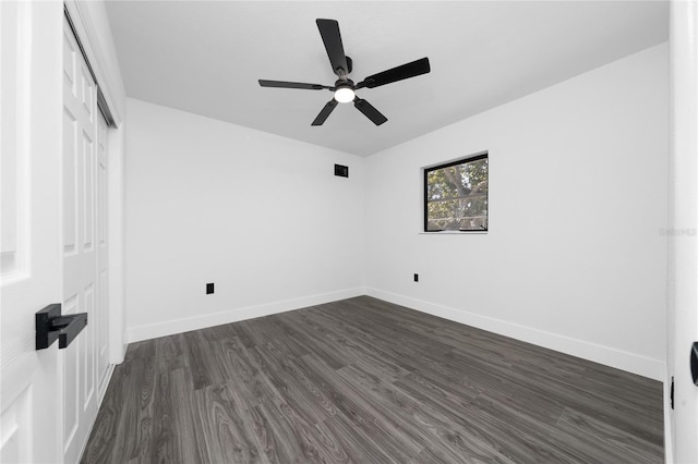 unfurnished bedroom featuring dark wood-style floors, a closet, baseboards, and a ceiling fan