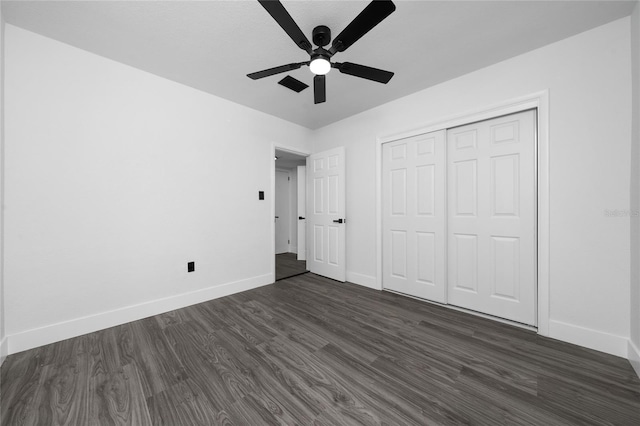 unfurnished bedroom featuring ceiling fan, baseboards, dark wood finished floors, and a closet