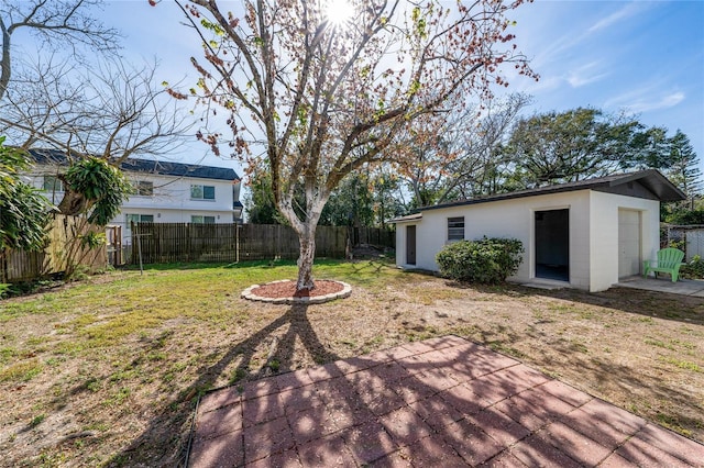 view of yard featuring an outbuilding, a fenced backyard, and a patio