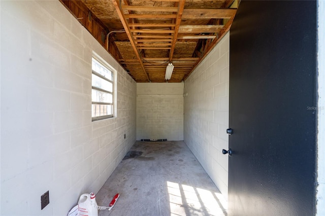 interior space featuring concrete block wall and unfinished concrete flooring