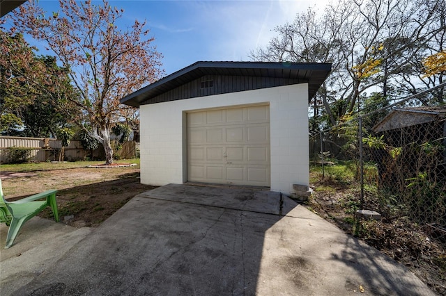 detached garage with concrete driveway and fence