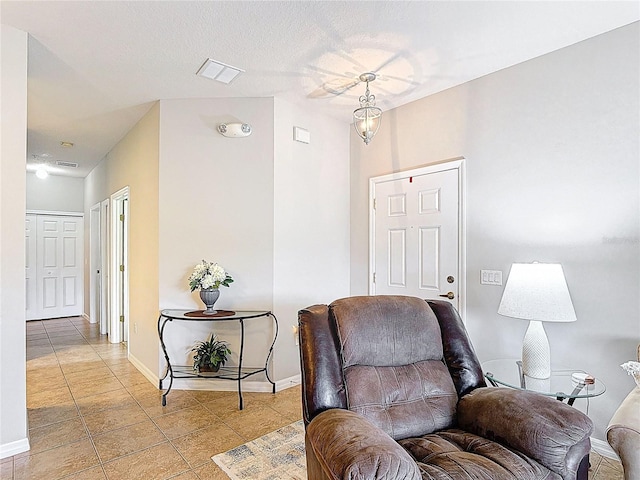 sitting room featuring light tile patterned flooring, baseboards, a textured ceiling, and visible vents