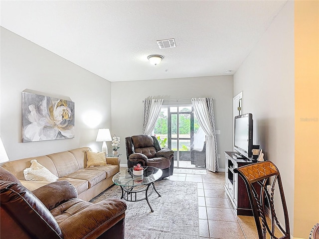 living room featuring baseboards, a textured ceiling, visible vents, and light tile patterned floors