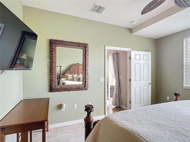 bedroom with baseboards, carpet flooring, a textured ceiling, and visible vents