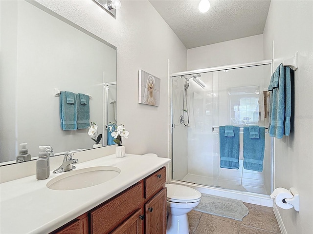 full bath featuring vanity, toilet, a shower stall, a textured ceiling, and tile patterned floors