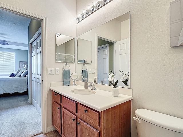 ensuite bathroom with connected bathroom, a textured wall, toilet, and vanity