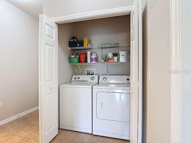 clothes washing area with baseboards, washing machine and dryer, laundry area, and light tile patterned floors
