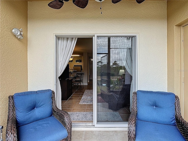 doorway to property featuring stucco siding and a ceiling fan