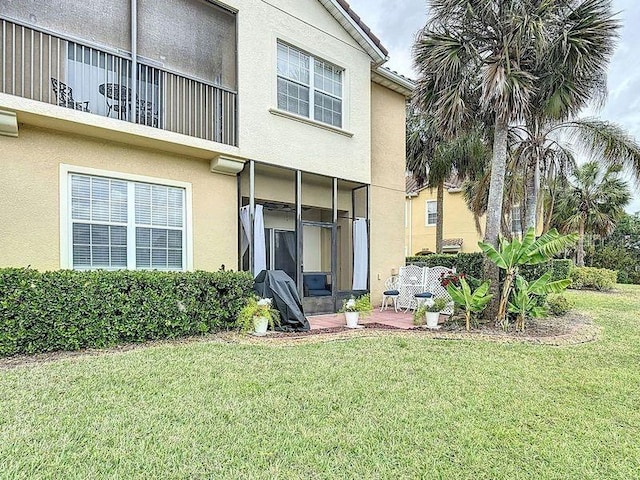 rear view of property featuring stucco siding and a yard
