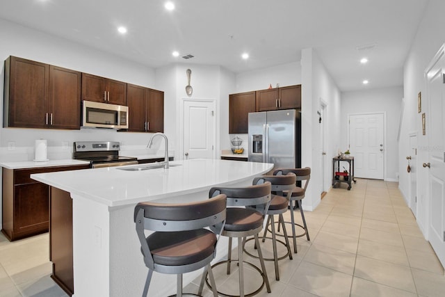 kitchen featuring sink, stainless steel appliances, a breakfast bar, and a center island with sink