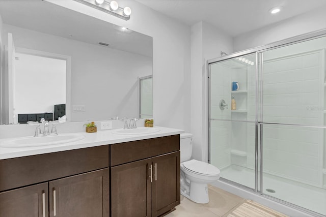 bathroom featuring vanity, a shower with shower door, tile patterned floors, and toilet