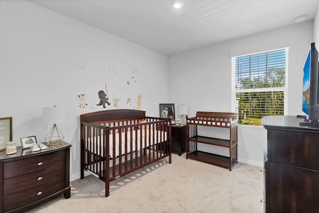 bedroom with light carpet and a nursery area