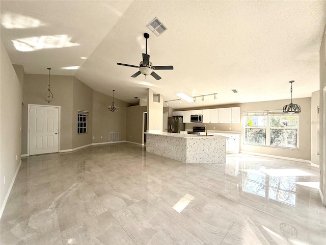 unfurnished living room featuring a textured ceiling, vaulted ceiling, and ceiling fan