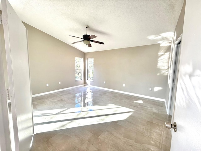 empty room with ceiling fan, vaulted ceiling, and a textured ceiling