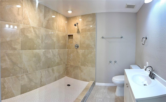 bathroom with tiled shower, vanity, and toilet