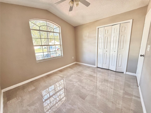 unfurnished bedroom featuring ceiling fan, a closet, vaulted ceiling, and a textured ceiling