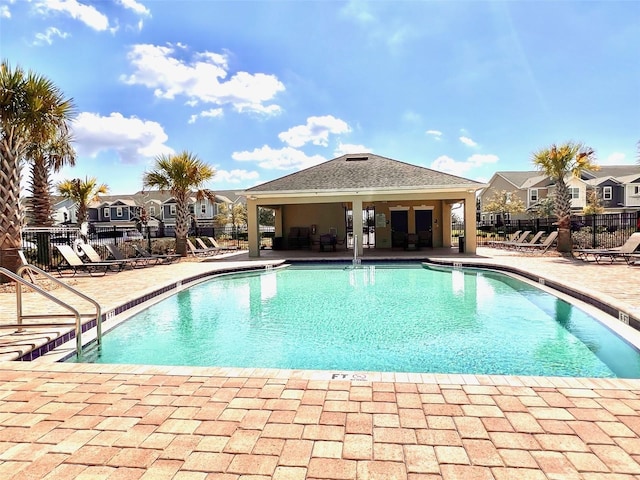 community pool with a patio area, a residential view, and fence