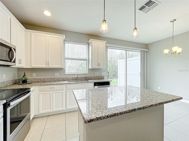 kitchen with light tile patterned floors, stainless steel appliances, visible vents, white cabinetry, and a sink