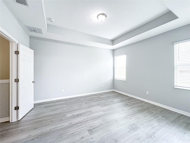 unfurnished room with visible vents, a textured ceiling, baseboards, and wood finished floors