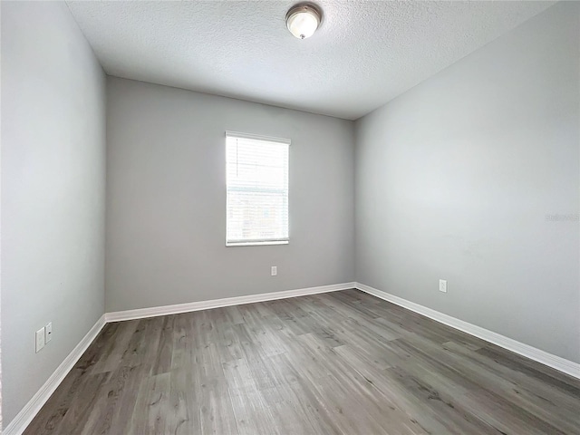 spare room featuring a textured ceiling, baseboards, and wood finished floors