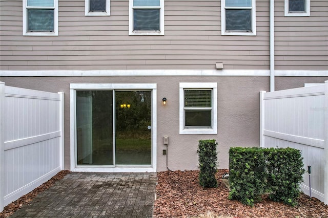 doorway to property featuring a patio area, fence, and stucco siding