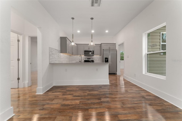 kitchen with pendant lighting, gray cabinetry, stainless steel appliances, tasteful backsplash, and kitchen peninsula