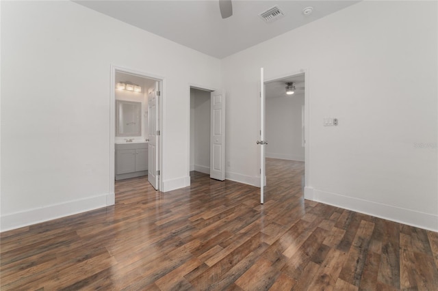 unfurnished bedroom with dark wood-type flooring, ensuite bath, and ceiling fan