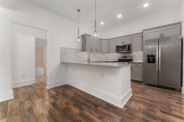 kitchen with dark wood-type flooring, sink, hanging light fixtures, appliances with stainless steel finishes, and kitchen peninsula