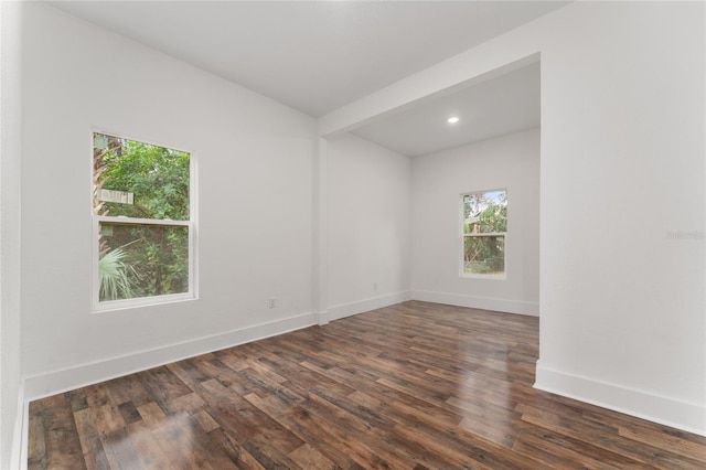 unfurnished room featuring dark hardwood / wood-style flooring and beamed ceiling