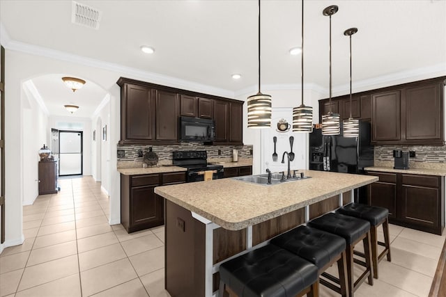 kitchen with pendant lighting, sink, a kitchen island with sink, black appliances, and a kitchen bar